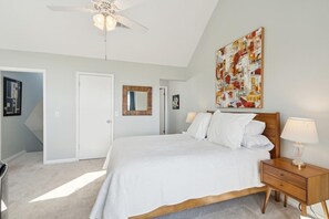 A bedroom with a bed, nightstand, and ceiling fan.