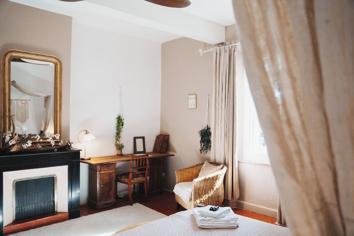 A room with a fireplace, a desk, a chair, and a bed.