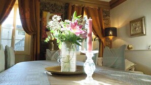 Ein Zimmer mit Esstisch, dekoriert mit Blumen und einer Kerze, einer Kandelaber und einer Lampe.