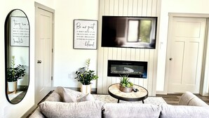 Un salon avec un canapé, un téléviseur fixé au mur et un miroir sur le mur.