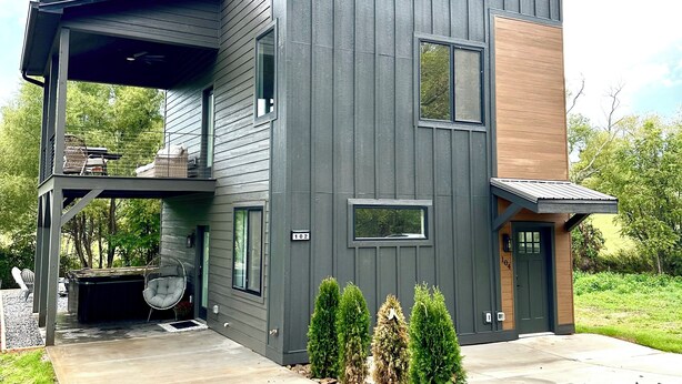 Une maison moderne à deux étages, dotée d’un porche abrité, d’un jacuzzi et d’une pelouse bien entretenue.