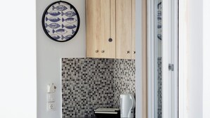 A compact kitchen with wooden cabinets, a tiled backsplash, and a built-in mini-fridge. - Eutixia house,Santorini  (santorini)