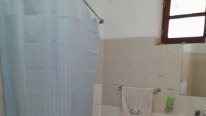 A bathroom with a bathtub, a sink, and a window. - The Hidden One (Praia)