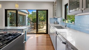 A modern kitchen with a large island, sliding glass doors to a patio, and a view of outdoor furniture.