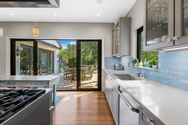A modern kitchen with a large island, sliding glass doors to a patio, and a view of outdoor furniture.
