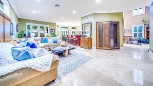 A spacious living room with a sofa, coffee table, and dining area. - 5 Bedroom Luxury Home, Minutes to Las Olas, Shops & Beach (Fort Lauderdale)