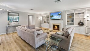 A modern living room with a fireplace, a television, and a glass coffee table.