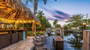 An outdoor bar area with a thatched roof, wicker chairs, and a wooden deck overlooking a body of water. - New Waterfront Oasis, Minutes to Beach, Eats, Shops (Fort Lauderdale)