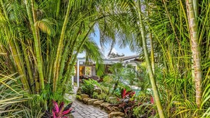 A pathway lined with bamboo and tropical plants leading to a building with a tiled roof. - New Waterfront Oasis, Minutes to Beach, Eats, Shops (Fort Lauderdale)