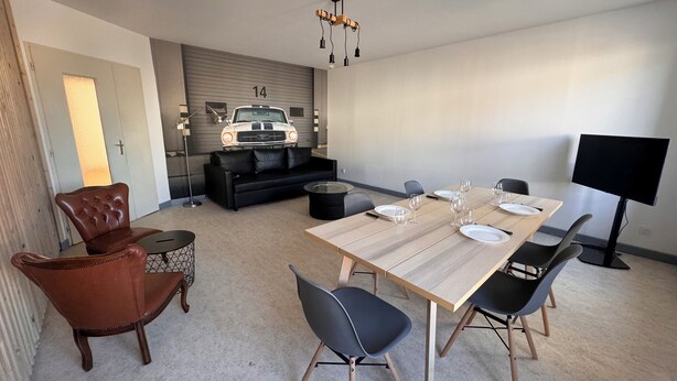 Una sala moderna con comedor, un sofá, un sillón de cuero, un modelo de coche y un televisor.