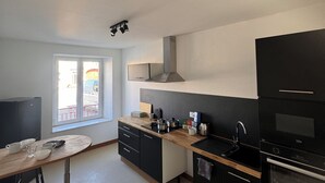 Una cocina moderna con armarios negros, encimera de madera y ventana con vistas a la calle.