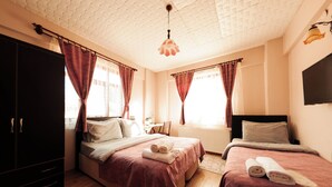 A hotel room with two beds, a wardrobe, a desk, and a television. - Abant Barış Pension (Bolu)