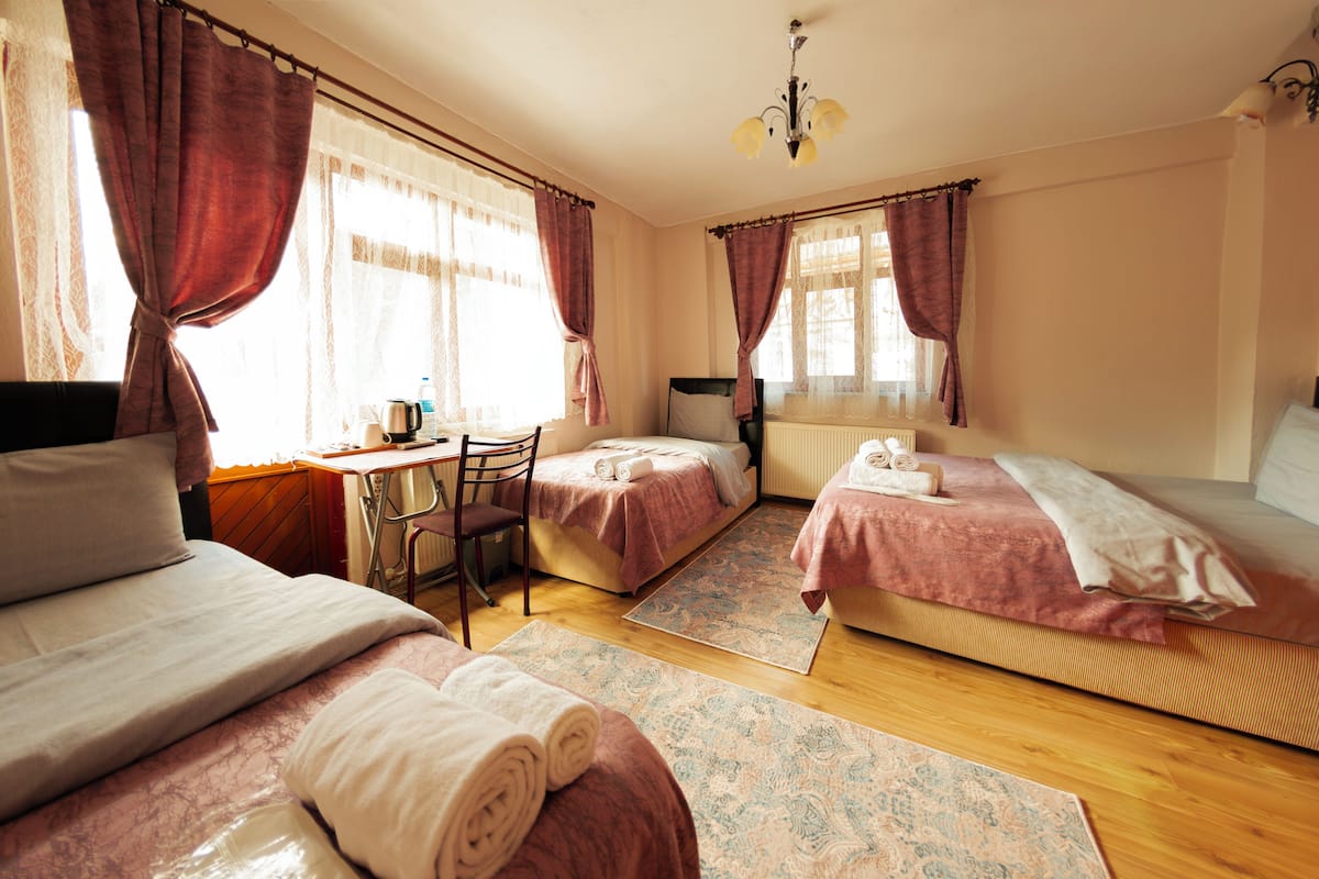 Quarto de hotel com duas camas, uma escrivaninha e uma cadeira.