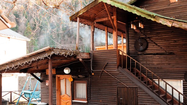 A wooden cabin with a porch, a swing set, and a staircase leading to the upper level. - Abant Barış Pension (Bolu)