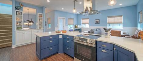 A modern kitchen with blue cabinetry, a central island, and a built-in oven.