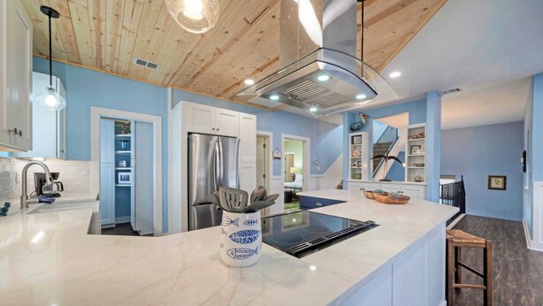 A modern kitchen with a marble countertop, stainless steel appliances, and a wooden ceiling. - Luxe Coastal Stay w/ Private Pool, Walk to Beach Leave of Absence by Avantstay (Port Aransas)