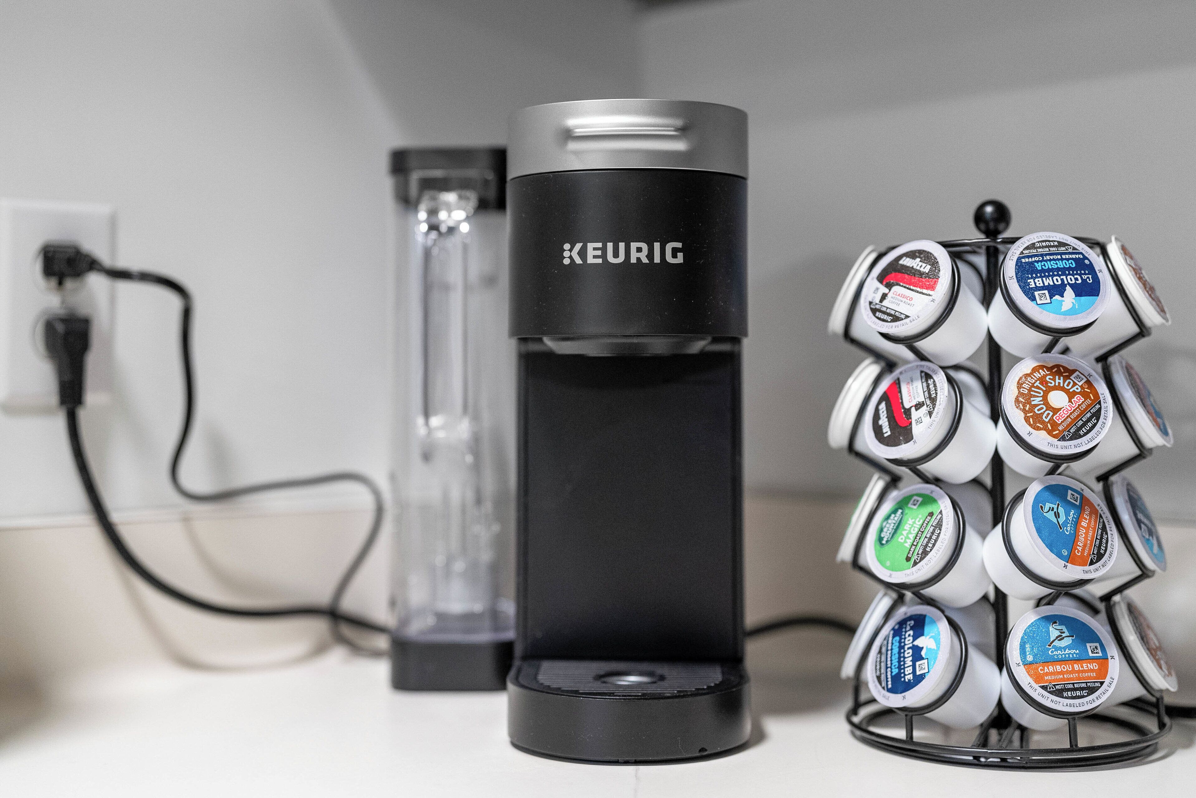 A Keurig coffee maker and a coffee pod holder with various coffee pods.