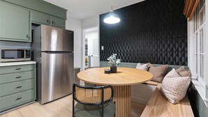 A modern kitchen with a stainless steel refrigerator, a microwave, and a round wooden table with a bench.