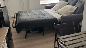 A compact bedroom with a bed, a small table, and a wardrobe.