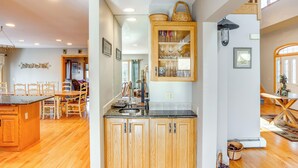 Cucina con mobili in legno, piano di lavoro in granito e zona pranzo con sedie e tavolo in legno.