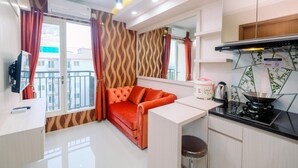 Un espace de vie compact comprenant un canapé, une kitchenette et une vue sur l’extérieur.