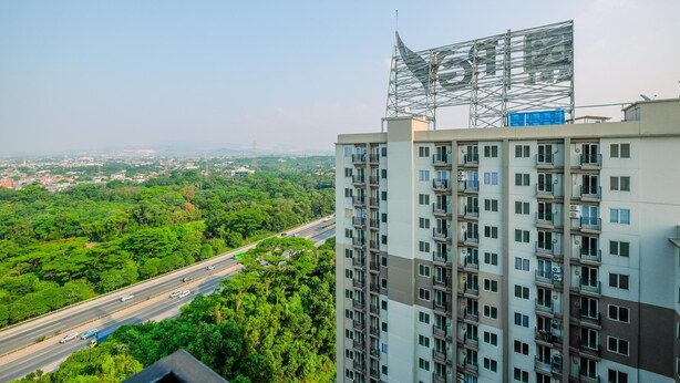 Un immeuble de grande hauteur doté de nombreux balcons et offrant une vue sur une autoroute et des espaces verts.