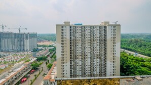 A high-rise building with multiple floors, surrounded by greenery and a road. - Best Choice and Tidy 2BR Podomoro Golf View Apartment (Gunung Putri)
