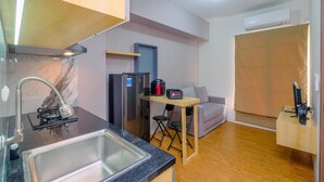 A compact kitchen with a sink, stove, and refrigerator. There is a small dining area with a table and chairs. - Best Choice and Tidy 2BR Podomoro Golf View Apartment (Gunung Putri)