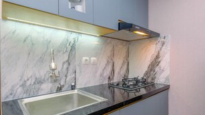 A modern kitchen with a marble backsplash, stainless steel sink, and a gas stove. - Best Choice and Tidy 2BR Podomoro Golf View Apartment (Gunung Putri)