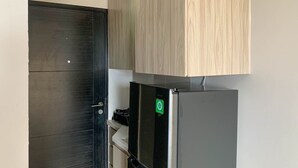 A kitchen with a black refrigerator, a wooden cabinet, and a door. - Cozy Studio at Belmont Residence Puri Apartment (Jakarta)