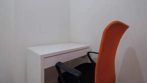 A white desk with a black chair and an orange chair. - Modern Look 2BR at Podomoro Golf View Apartment (Gunung Putri)