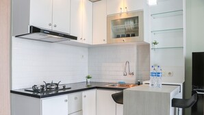 A modern kitchen with white cabinets, a black countertop, a stove, and a dishwasher. - Spacious and Good 2BR at Podomoro Golf View Apartment (Gunung Putri)