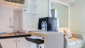 A modern kitchen with a built-in sink, a black refrigerator, and a white countertop. - Spacious and Good 2BR at Podomoro Golf View Apartment (Gunung Putri)