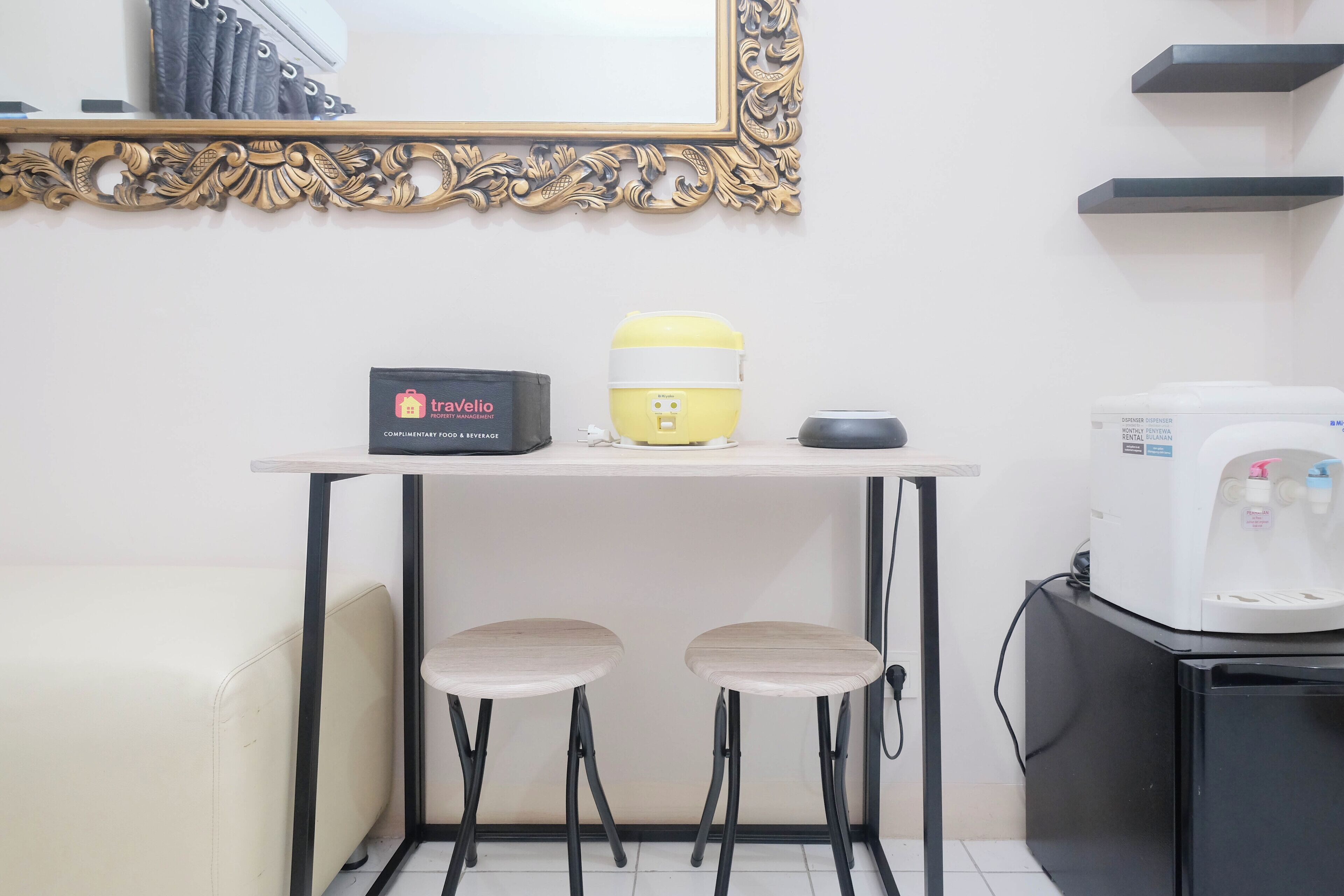 Una kitchenette pequeña con microondas, cafetera y una bolsa de viaje sobre la encimera.