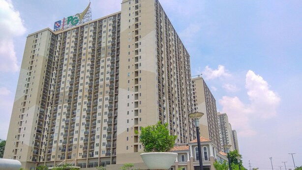 A high-rise residential building with multiple balconies and a PG logo on the top.