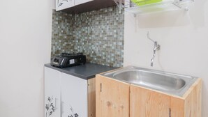 A kitchen with a tiled backsplash, a sink, and a countertop with a coffee maker.