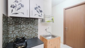 A kitchen with a gas stove, a sink, and a wooden cabinet.