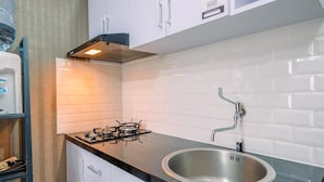 A modern kitchen with white cabinets, a stainless steel sink, and a gas stove.