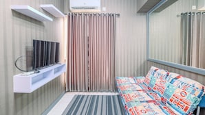 A modern room with a flat-screen TV on a white shelf, a patterned sofa, a striped rug, and a large mirror reflecting the room.