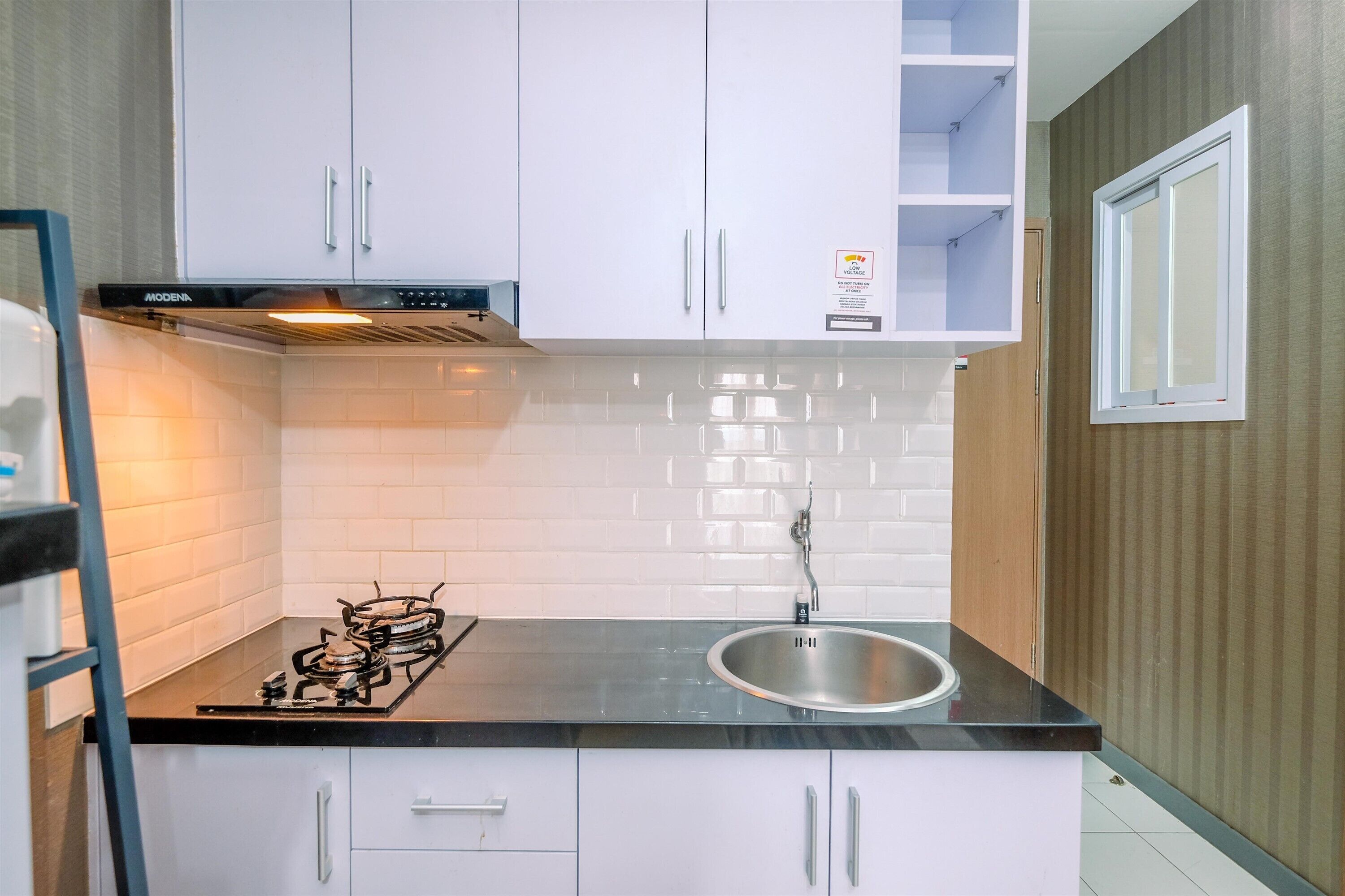 A modern kitchen with white cabinets, a stainless steel sink, and a gas stove.