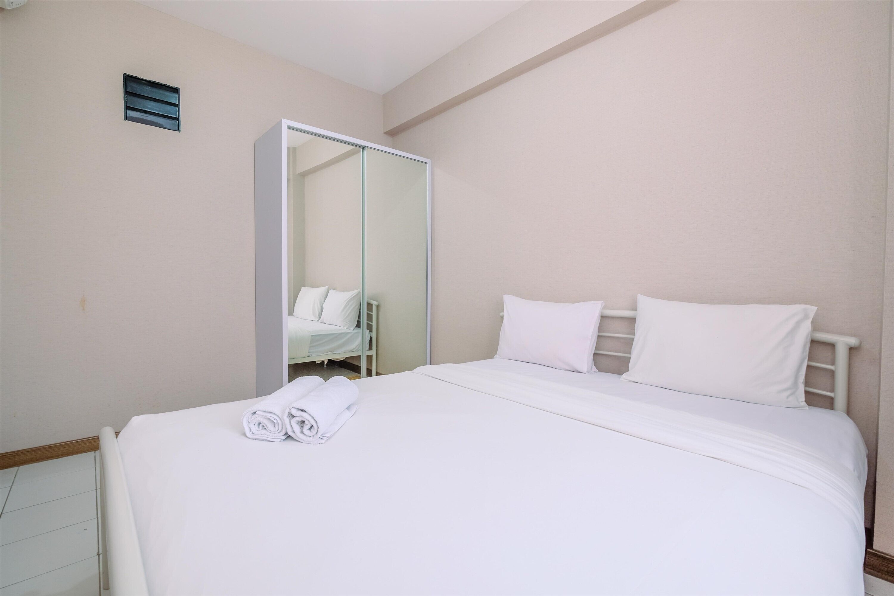 A hotel room with a large bed, a wardrobe, and a mirror.