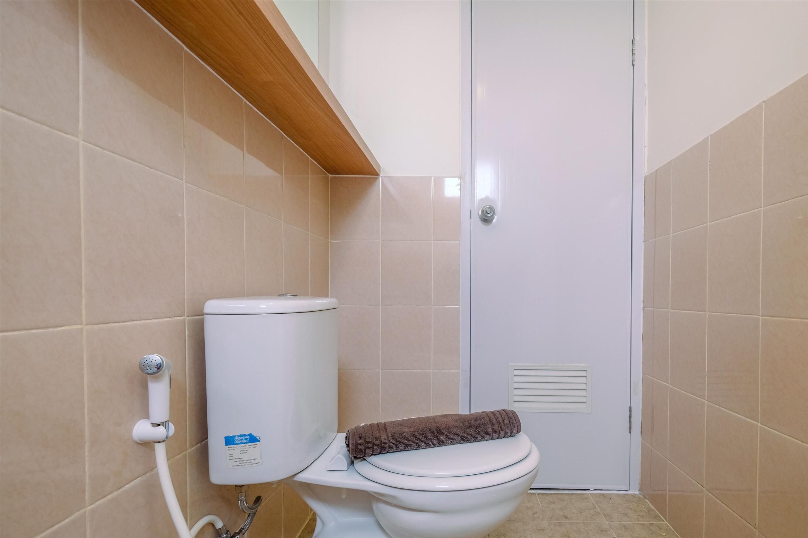 Een badkamer met een toilet, een handdoek en een douchekop.