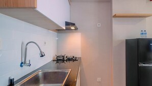 Eine moderne Küche mit einem Edelstahlspülbecken, einem Gasherd und einem schwarzen Kühlschrank.