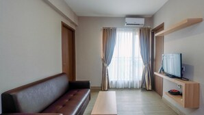 Ein modernes Wohnzimmer mit einer Couch, einem Couchtisch, einem Fernseher auf einem Holzregal und einem Fenster mit Vorhängen.