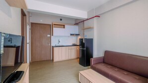 Ein kompakter Wohnbereich mit Küchenzeile, einem braunen Sofa und einer hölzernen Bank.