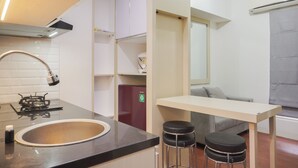 Eine moderne Küche mit Gaskochfeld, Spüle und Barhocker. Ein Kühlschrank und ein Fenster sorgen für natürliches Licht.