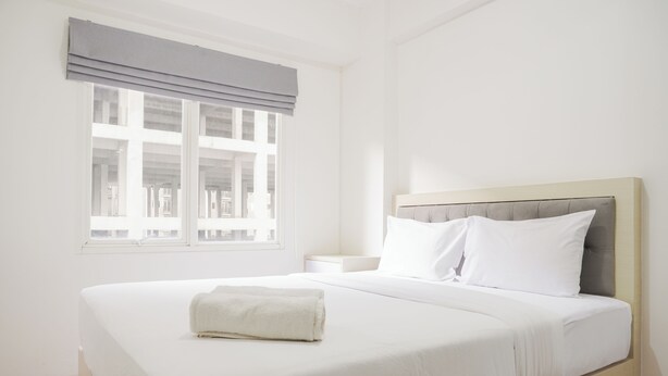 Ein Hotelzimmer mit einem großen Bett, einem Fenster mit Jalousien, einem Nachttisch und einem Beistelltisch.