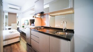 A modern kitchen with a gas stove, stainless steel sink, and white cabinetry. - Homey and Simple Studio at Tanglin Supermall Mansion Apartment (Surabaya)