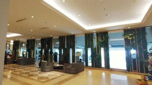 A spacious lobby with a checkered floor, modern lighting, and large windows with green curtains. - Homey and Simple Studio at Tanglin Supermall Mansion Apartment (Surabaya)