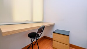 Une pièce d’angle avec un bureau en bois, une chaise noire et un petit meuble en bois.